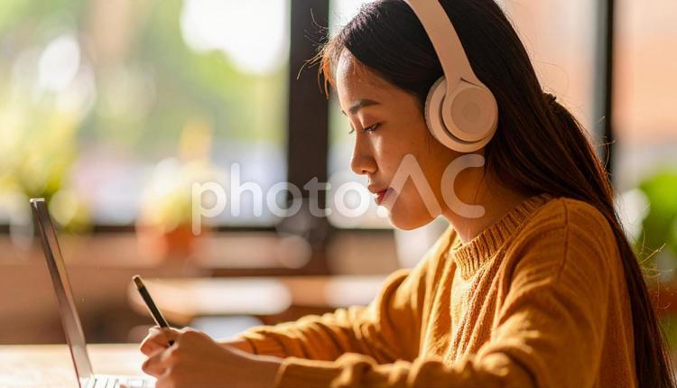 お気に入りの音楽を聴きながら勉強する女性 勉強,ノートパソコン,女性の写真素材