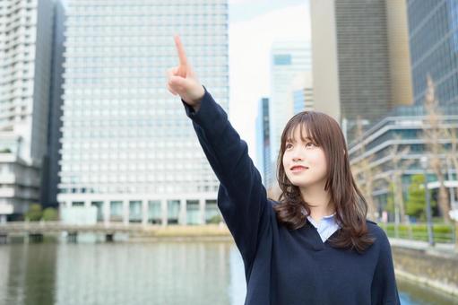 ビル街で大きく指をさす女子高生 ビル街で大きく指をさす女子高生 高校生,女子高生,指さしの写真素材