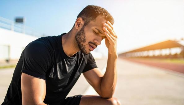 暑さでダウンし、しゃがみ込む外国人男性 暑さでダウンし、しゃがみ込む外国人男性の写真