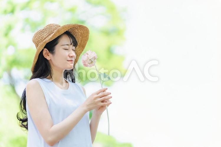 一輪の花を持つ女性（帽子） 花,一輪,花束の写真素材