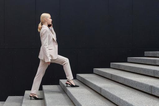 オフィスビルの外の階段を登りながら電話している横向きのビジネスウーマン ビジネスウーマン,ビジネス,女性の写真素材