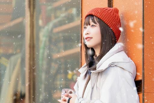 雪の降る冬の街角に立つ笑顔の女性 冬,雪,女性の写真素材
