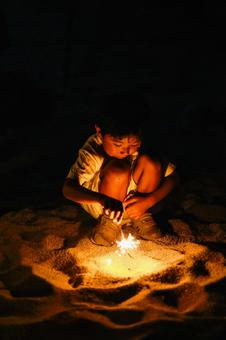 夜の砂浜で花火をする男の子 夜の砂浜で花火をする男の子 砂浜,夜,花火の写真素材