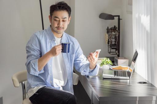 コーヒーを飲みながらスマホを使う男性 コーヒーを飲みながらスマホを使う男性 ビジネスマン,ノートパソコン,コーヒーの写真素材