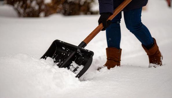 大雪が降った日の翌日の朝に雪かきする女性 大雪が降った日の翌日の朝に雪かきする女性の写真