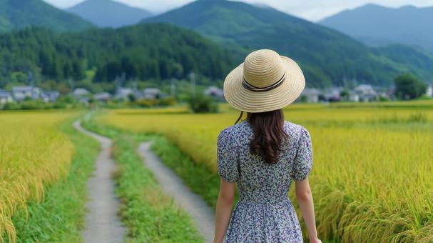 田園風景の道を歩くワンピース姿の女性の写真