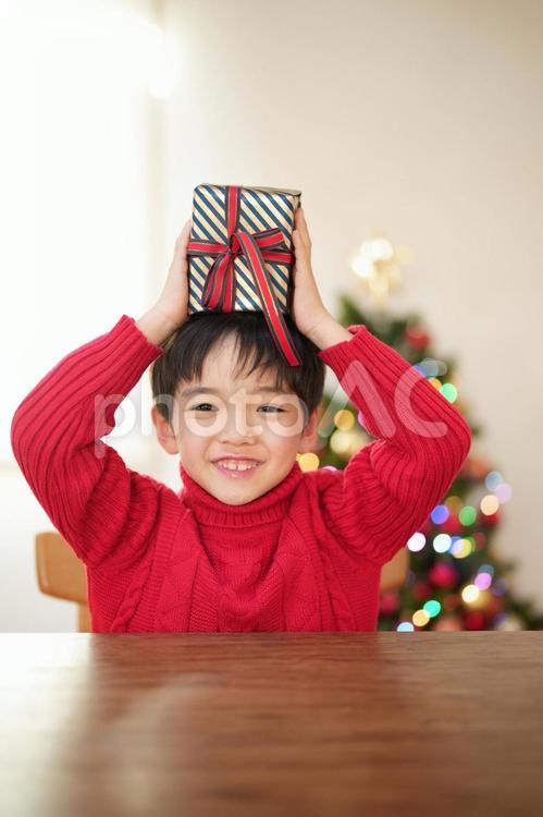 カメラ目線で頭の上でプレゼントを持つ男の子 男の子,プレゼント,リボンの写真素材