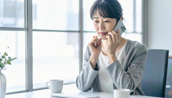 困った表情で電話する中年 困った表情で電話する中年の写真