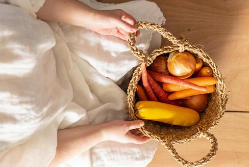 オレンジ色の野菜が入ったカゴを持つ手 オレンジ色の野菜が入ったカゴを持つ手 野菜,カゴ,持つの写真素材