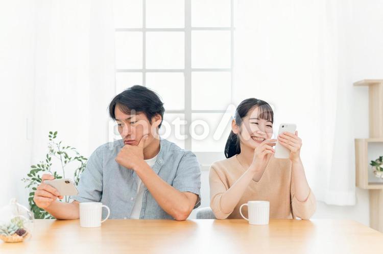 お互いにスマホを見る夫婦（笑顔） スマホ,居心地,夫婦の写真素材