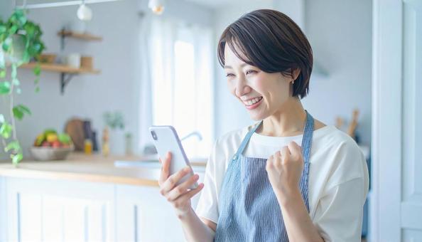 スマホでポイ活する笑顔の女性 スマホでポイ活する笑顔の女性の写真