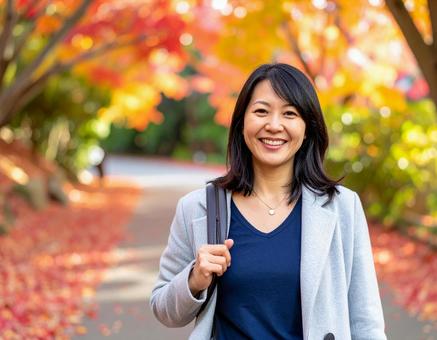 紅葉の道を散歩する女性の写真