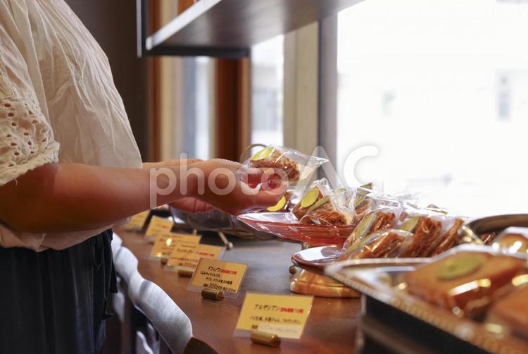 洋菓子店で焼き菓子を手に取る女性 洋菓子,焼き菓子,スイーツの写真素材