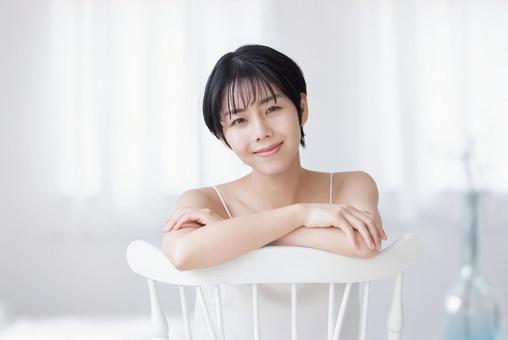 A young woman in a camisole sitting across a chair, JPG A young woman in a camisole sitting across a chair, JPG