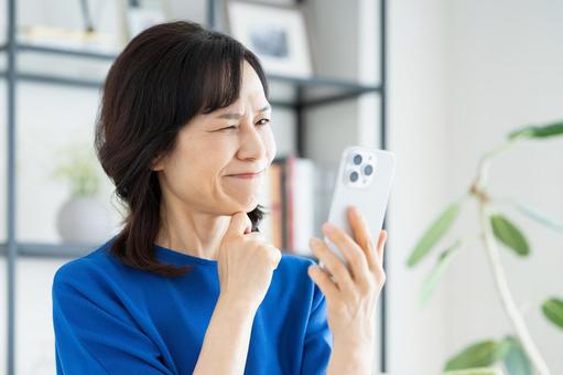 スマホで悩むミドルの女性 スマホで悩むミドルの女性 悩む,スマホ,女性の写真素材
