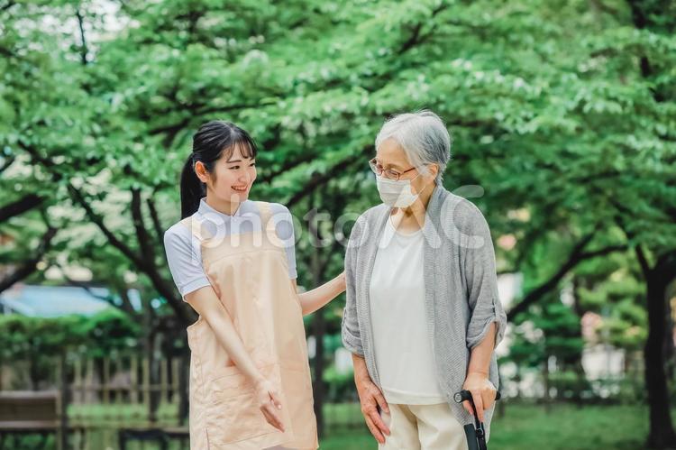 高齢者をサポートするエプロン姿の女性（杖） 介護,介護福祉士,介護士の写真素材