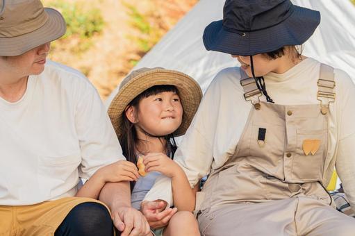 キャンプ場でパンを食べる子どもと両親 キャンプ,家族,子供の写真素材