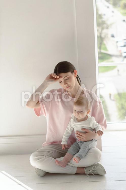 目を瞑って赤ちゃんを抱っこして休憩する女性 親子,女性,人物の写真素材