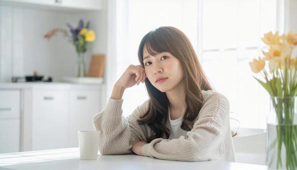 疲れた表情でキッチンに座る若い女性の写真