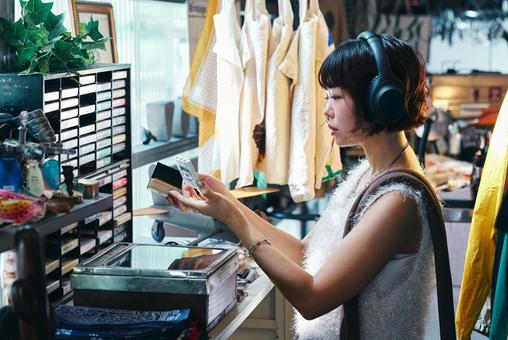 店頭でカセットテープを手に取る若い女性 店頭でカセットテープを手に取る若い女性 カセット,サブカル,カセットテープの写真素材