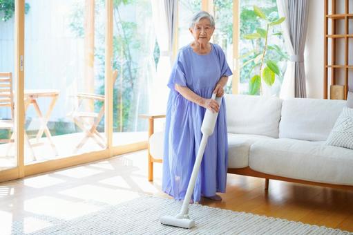 白い掃除機を持ちカメラ目線のおばあちゃん 女性,掃除,掃除機の写真素材