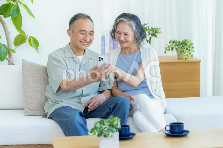 リビングでスマホを見るシニア夫婦 スマホ,シニア,笑顔の写真素材