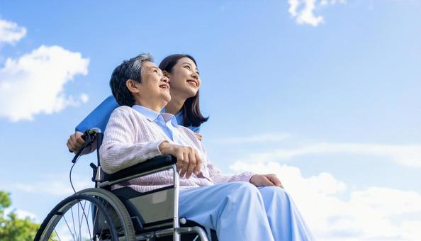 青空を見つめる車いすシニアと介護の女性 青空を見つめる車いすシニアと介護の女性の写真