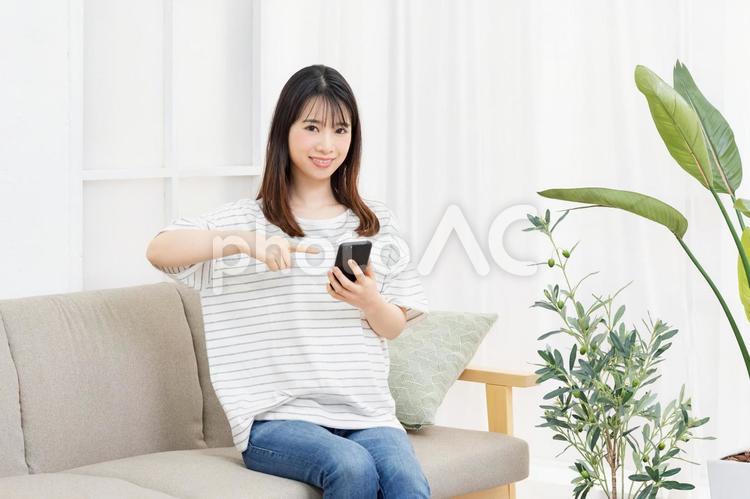 部屋のソファーに座ってスマホを操作する若い女性 女性,スマホ,ソファの写真素材