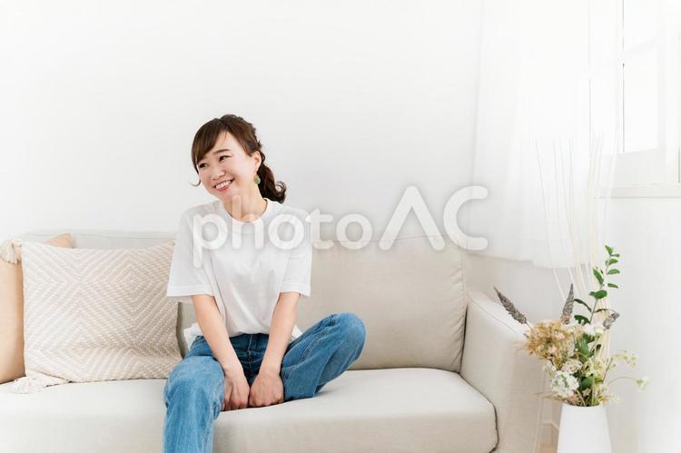 家のソファに座る笑顔の日本人女性（話す） 女性,笑顔,ソファの写真素材