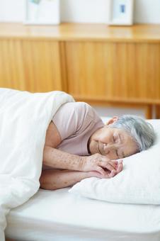 横向きで睡眠中の高齢女性 女性,寝る,目を瞑るの写真素材