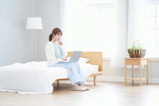 ベッドに座りパソコンを見て悩む女性 女性,ノートパソコン,座るの写真素材