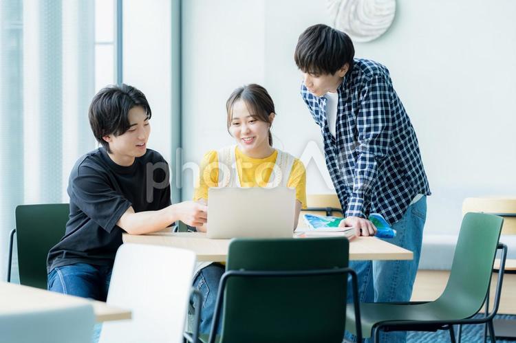 パソコンを見ながら話す学生たち 大学生,笑顔,学校の写真素材