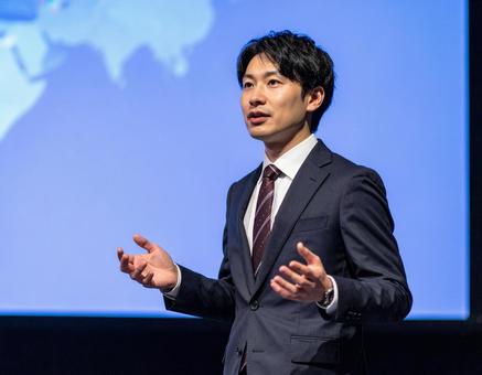 ステージ上で堂々とプレゼンする男性 ステージ上で堂々とプレゼンする男性の写真