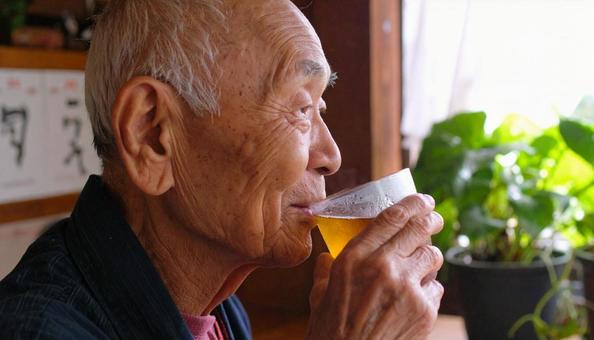 屋内で麦茶を飲むシニア男性 屋内で麦茶を飲むシニア男性の写真