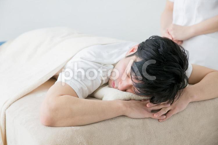 施術台で眠る男性 20代,2人,30代の写真素材