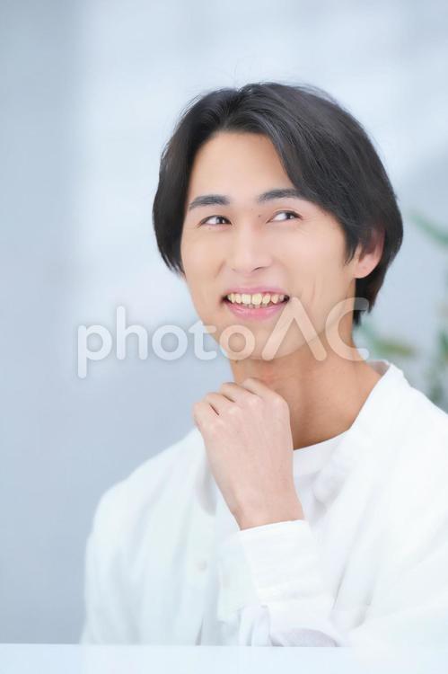 はにかみながら遠くを見て話す男性（縦） 男性,美容男子,化粧男子の写真素材