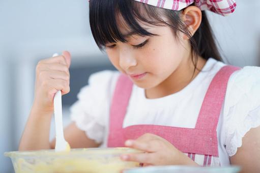 生地を混ぜるエプロン姿の女の子の手元 女の子,小学生,日本人の写真素材