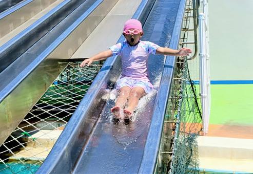ウォータースライダーを滑り降りる女の子 プール,ウォータースライダー,水遊びの写真素材