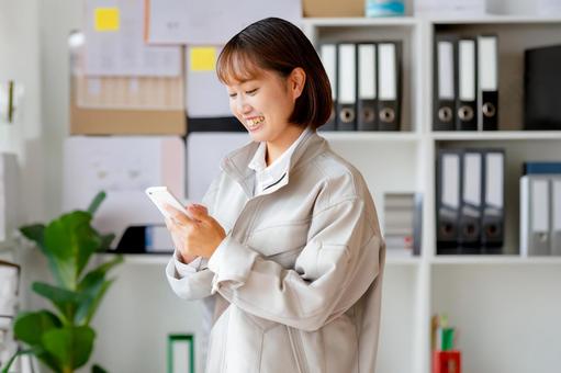 スマホと作業服女性 スマホと作業服女性の写真