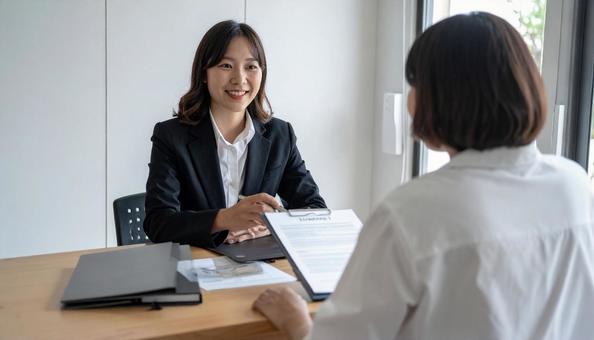 対面で客に説明する笑顔の日本人の働く女性 対面で客に説明する笑顔の日本人の働く女性の写真