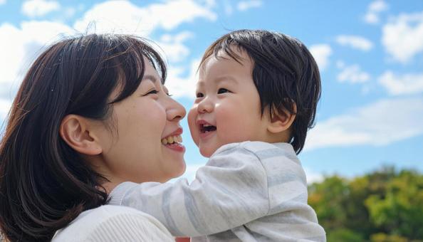 青空の下、子供を抱っこする母親 青空の下、子供を抱っこする母親の写真