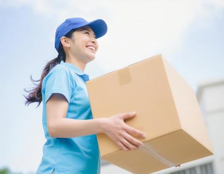大きいダンボール荷物を運ぶ笑顔の女性 大きいダンボール荷物を運ぶ笑顔の女性の写真