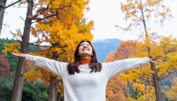紅葉の中で深呼吸する秋服の日本人女性 紅葉の中で深呼吸する秋服の日本人女性の写真