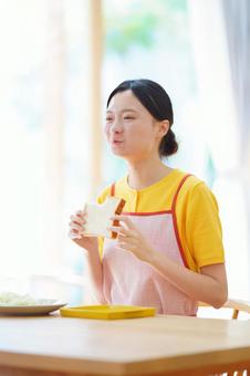 両手で食パンを持ち食べている女性 女性,朝食,食パンの写真素材