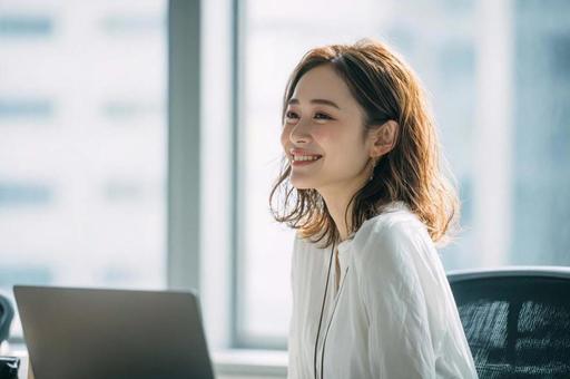 デスクでほほ笑むビジネス女性 デスクでほほ笑むビジネス女性の写真