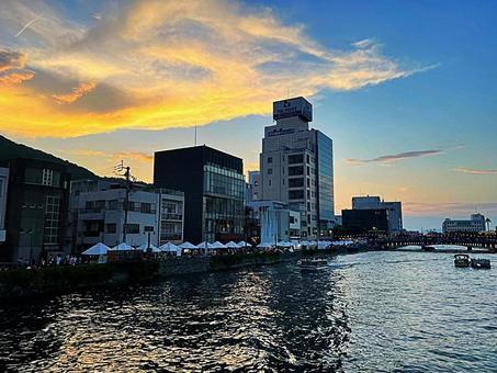 夕暮れの川沿いと賑わう屋台の風景の写真