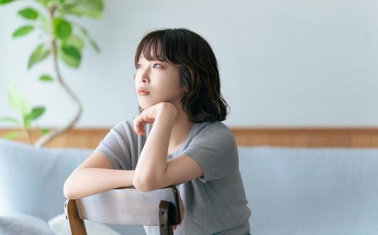 椅子に座って考えごとをする女性 女性,考える,困るの写真素材