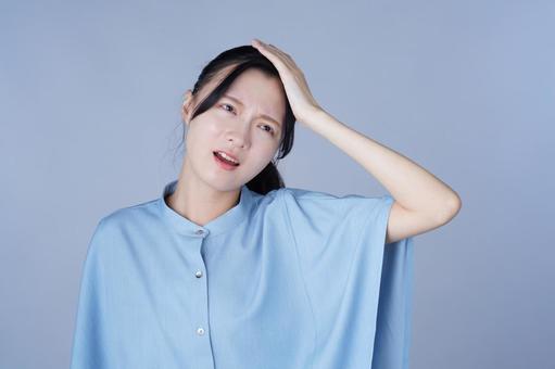 頭を抱えている青い服の女性 女性,頭を抱える,困るの写真素材