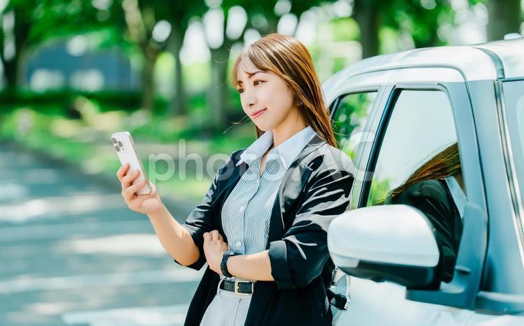 車にもたれてスマホを見る女性 女性,車,運転の写真素材