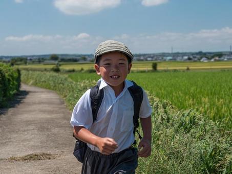 田んぼの道を走る男の子 田んぼの道を走る男の子の写真